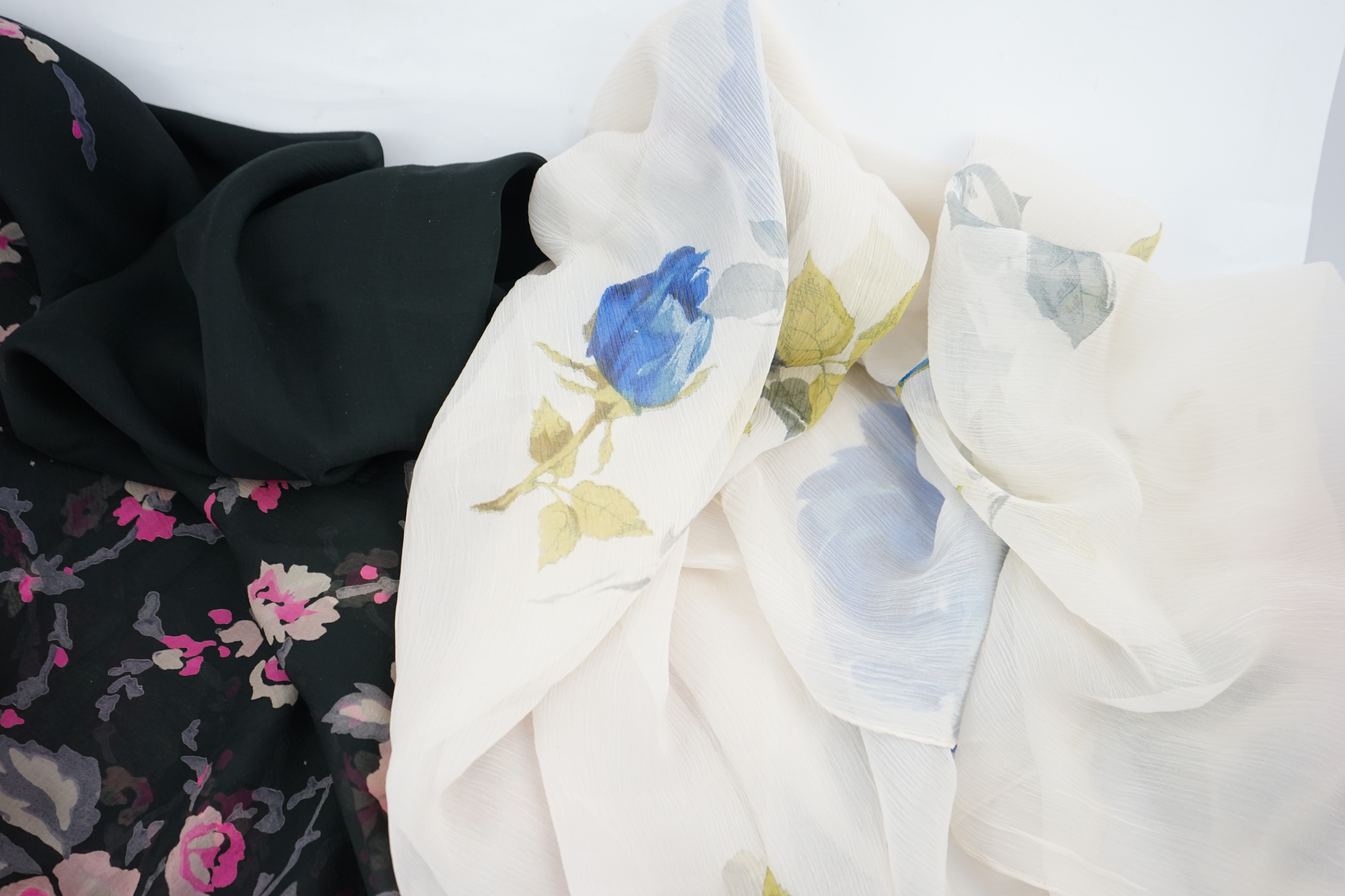 Three 1950s silk chiffon evening stoles, one cream crepe de chine designed with large red and blue single stem roses, another black silk chiffon with wide pink rose border, the other a plain coral chiffon, cream stole 18